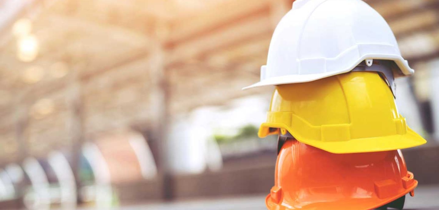 Imaxe dunha obra. Na parte dereita poden verse tres cascos colocados un enriba doutro ( laranxa, amarelo e branco). O fondo da imaxe é en tonos de cor crema.