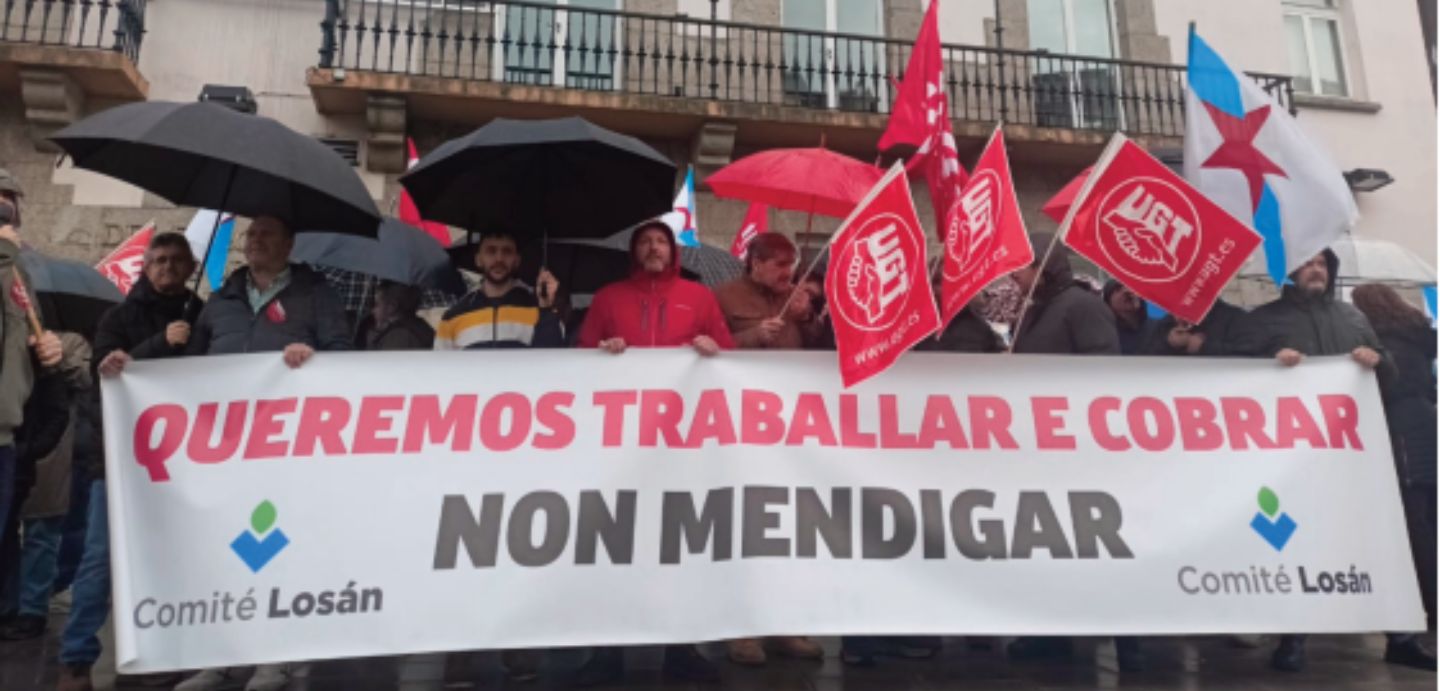 Imaxe da concentración diante da Delegación do Goberno na Coruña. Lema da pancarta: "Queremos traballar e cobrar. Non mendigar"