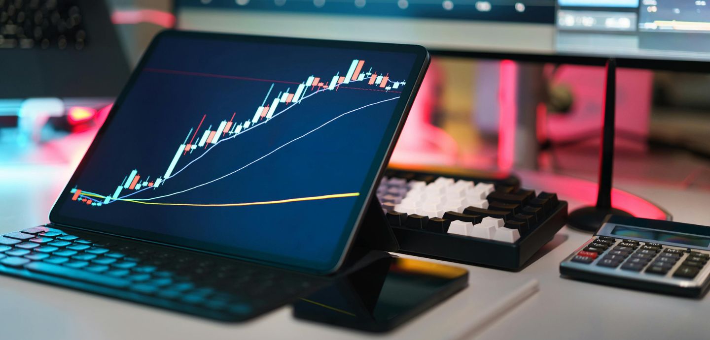 Na imaxe móstrase unha mesa, enriba del está colocada unha tablet cun teclado. Na imaxe da tablet se atopa un gráfico de barras. Ao lado da tablet atópase un teléfono e unha calculadora.