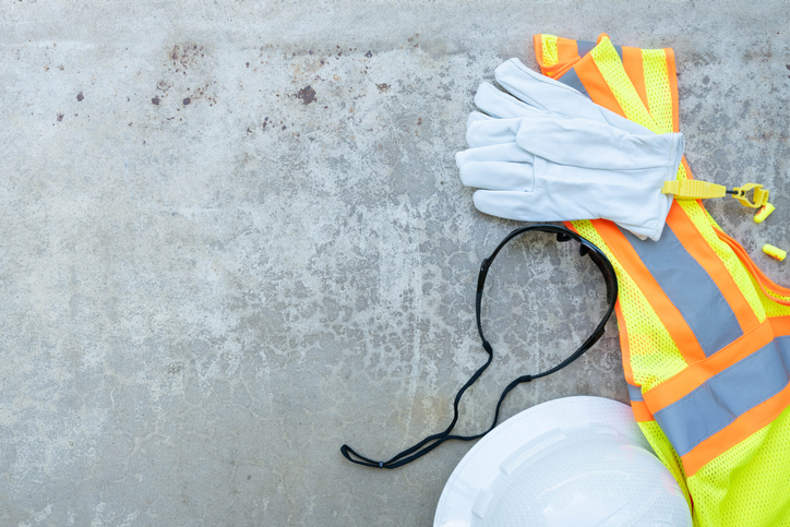 Casco, luvas, lentes, tapons e chaleco colocado nun fondo gris